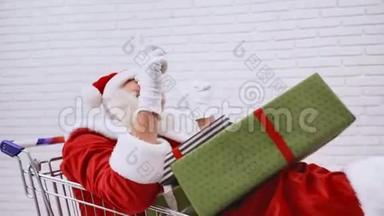 <strong>圣诞</strong>老人坐在购物车里拿着礼品盒